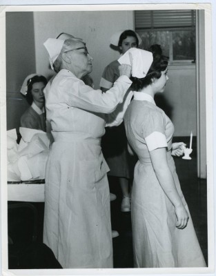  A nurse, possibly Molly Roseman, pinning a cap on a student nurse in a capping ceremony. 