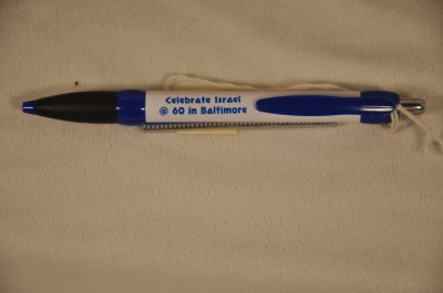 White plastic pen with blue details imprinting, Celebrate Israel @ 60 in Baltimore with double-sided pull-out scroll with information about www.israel60baltimore.com and facts about Israel.  Courtesy of Duke Zimmerman. 2008.40.1.