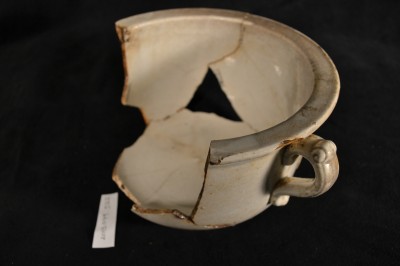 An ironstone chamberpot with decorative molded handles.