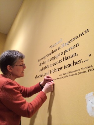 Curator Karen Falk removes wall text in preparation for our next exhibit - Project Mah Jongg!