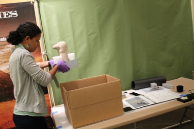 First, Joanna Church, the Collections Manager, and the conservators, moved out the fragile and valuable objects such as Mendes’s flag. Pictured here is one of the conservators using nitrile gloves to handle objects.