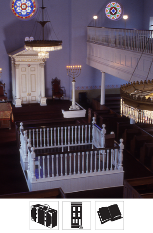 An interior photo of the Lloyd Street Synagogue from the second floor, showing the bimah, holy ark, chandeliers, and stained glass windows.