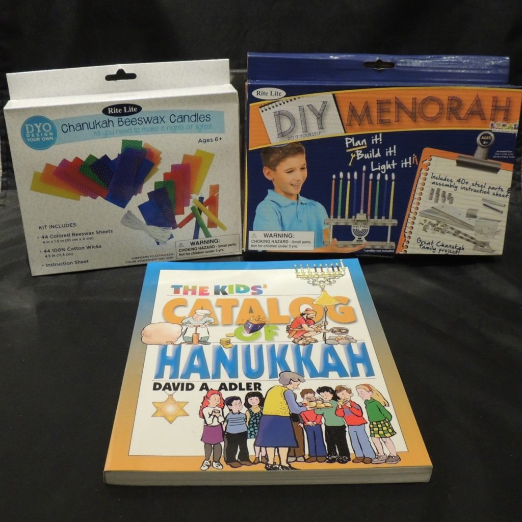 Photo showing a box of make your own hanukkah beeswax candles, a DIY menorah building kit and a book called The Kids' Catalog of Hanukkah.
