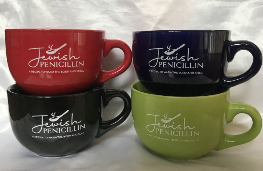 Four large soup mugs in black, red, and green. On each mug is text reading "Jewish penicillin a recipe to warm the body and soul."