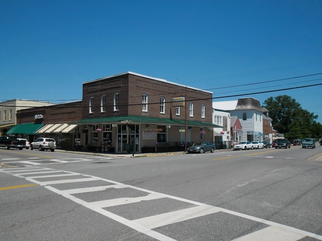 Street intersection with crosswalk. Brown brick building with green awning in the background.