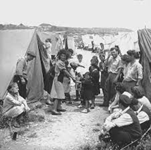 A group of people gather around between two tents, including adults and children.